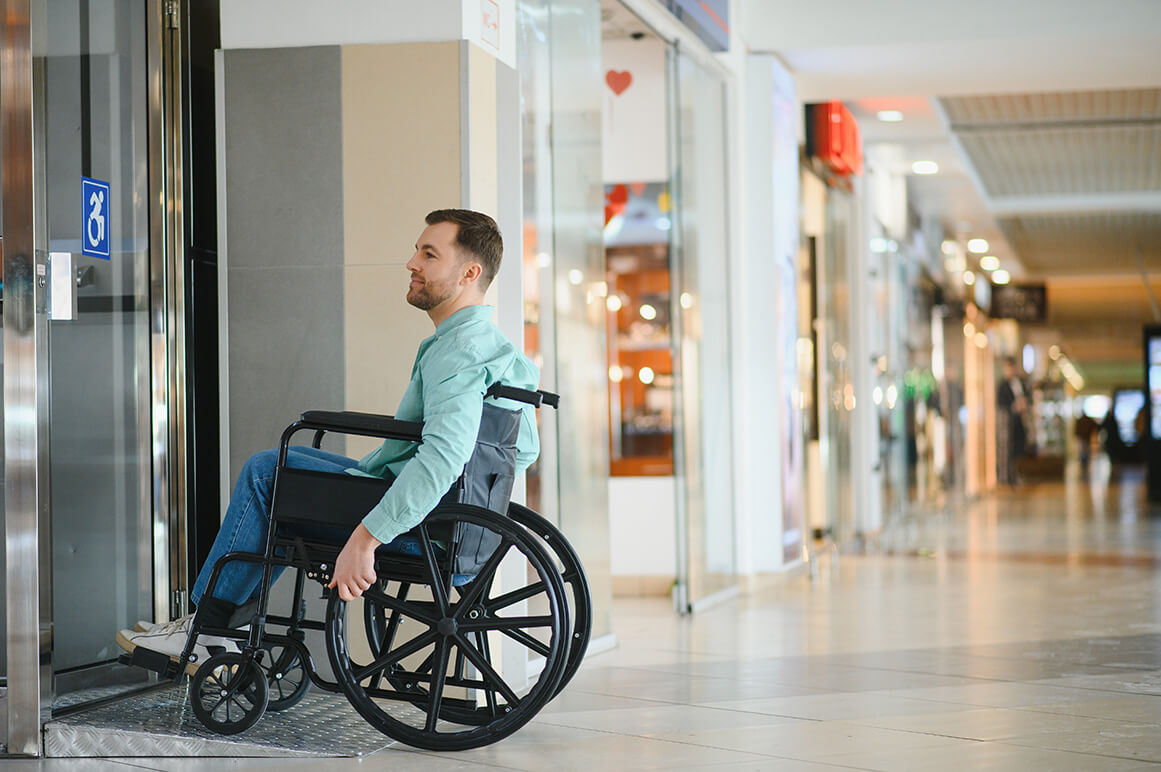 Normes ERP, homme en fauteuil roulant devant une entrée