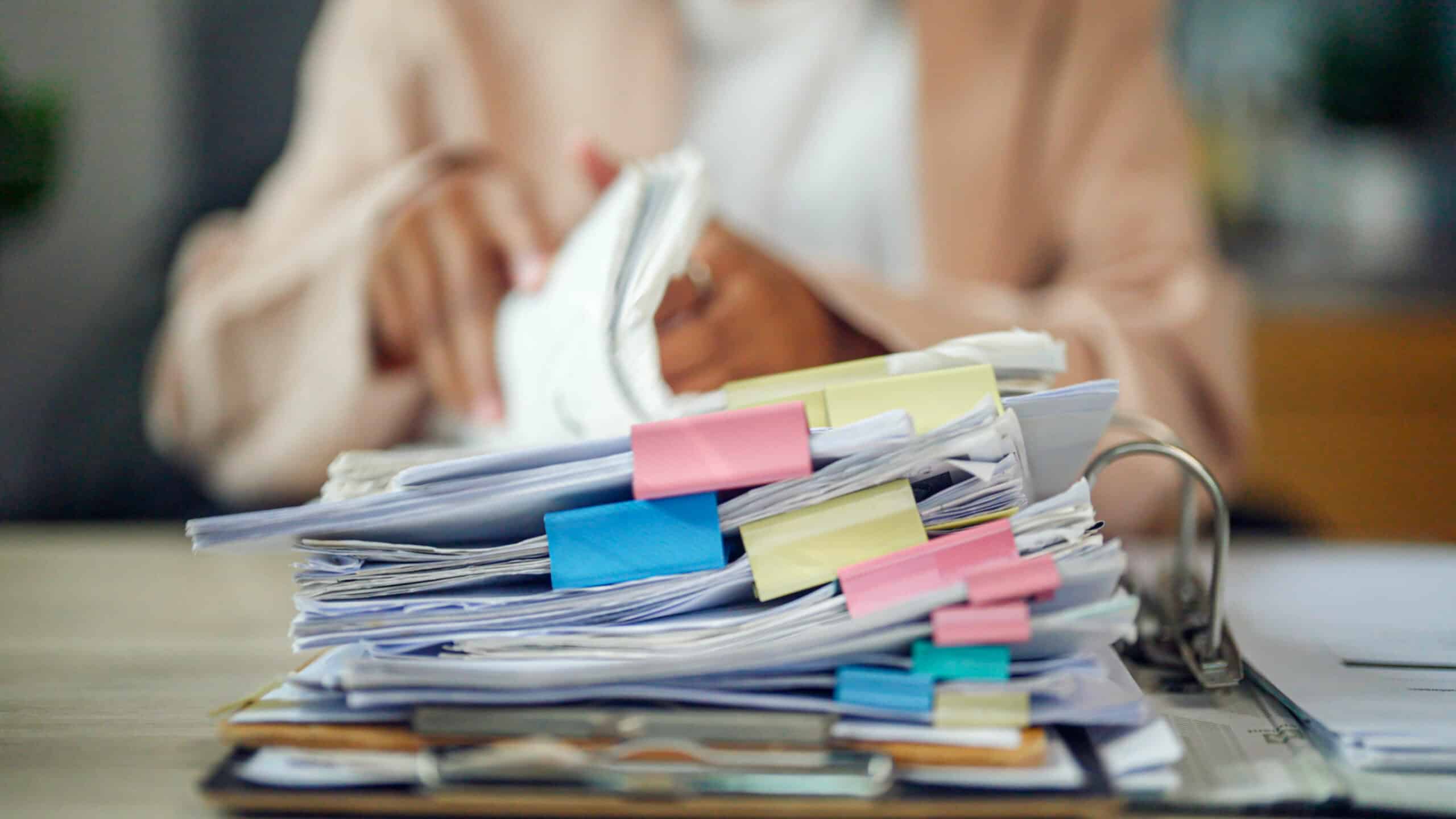 Pile de feuille et de dossier erp avec un personne flouté en arrière plan